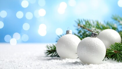 Elegant white Christmas ornaments nestled in fresh snow with festive blue bokeh lights.