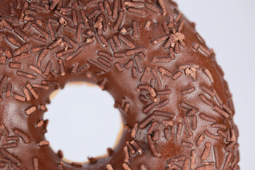 Extreme Close Up Of A Sweet Doughnut Glazed With Chocolate. Focus On The Sugar Sprinkles And Glossy Icing.