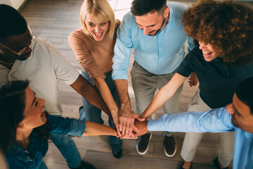 High angle shot of a diverse business team stacking hands, smiling and celebrating unity and teamwork