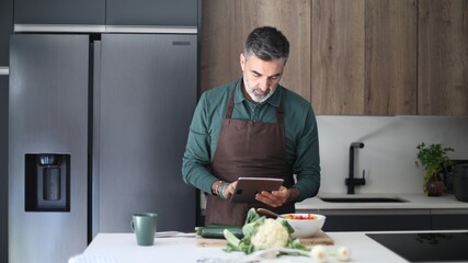 Man cooking healthy meal using digital tablet