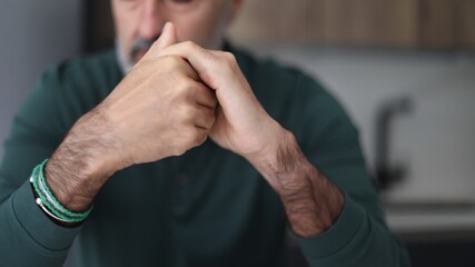 Mature man concentrating with clasped hands thinking