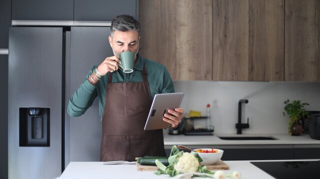 Man cooking healthy breakfast checking recipe on tablet