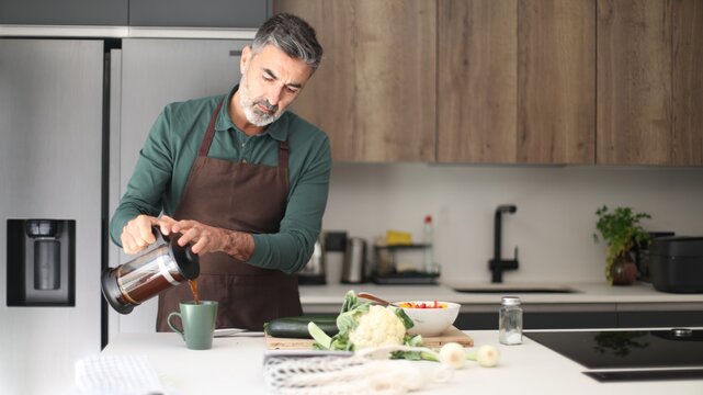 Man pouring fresh coffee in modern kitchen