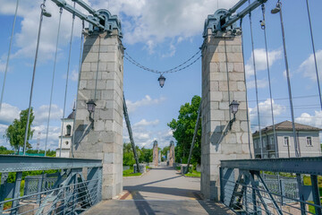 Fototapeta premium Massive stone pylons and steel cables of Ostrov’s historic suspension bridge over the Velikaya River in Pskov oblast, Russia. stock photo 