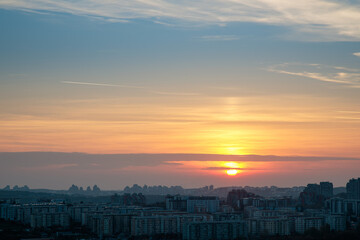 Pale orange and blue winter sunset over a dense residential cityscape with high-rise buildings.