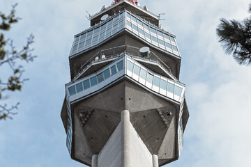 Low-angle view of the Avala tower's observation deck and antenna structure against a bright, overcast sky, Belgrade, Serbia.