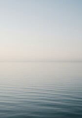 Obraz premium A vast, quiet surface of still water reflecting soft light under a pale sky, evoking deep tranquility and peaceful emptiness, suitable for copy space ,clarity ,soft ,natural