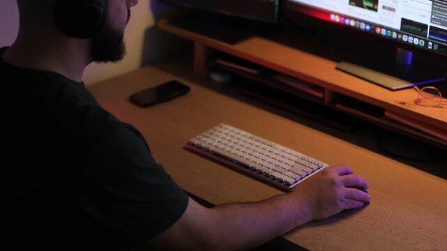 Remote worker using computer at desk in low light home office