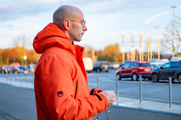 casual portrait bald man and bright orange jacket standing outdoors, stylish male in bright orange outerwear autumn or winter day, urban style with warm winter essentials, everyday urban life