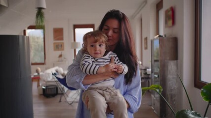 Mother holding toddler in bright living room creating warm affectionate moment filled with connection tenderness and natural family comfort