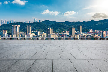 Empty square floor and modern city buildings with green mountain under blue sky