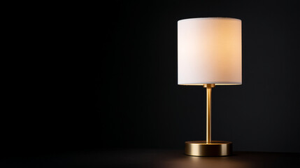 A minimalist table lamp with a white shade and gold base on a dark surface creates a warm glow