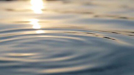 Extreme close-up slow motion shot of an absolutely calm, pristine surface of clear water reflecting ambient soft light minimal, liquid movement, fluidity