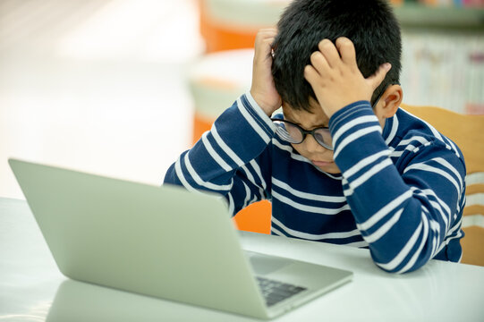 A focused student works on a laptop in a library, representing studying, digital education, childhood learning, academic research, and modern technology use.
