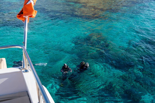 Divers Exploring Crystal Clear Waters Near a Boat During Bright Daylight in a Tropical Location