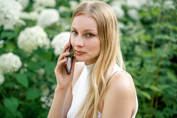 A woman is taking a selfie in front of white flowers