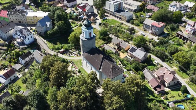 Aerial drone view of Zulova town in the Czech Republic historic church on Bozi Hora hill, traditional rooftops, surrounding greenery, and the peaceful town layout captured in clear daylight