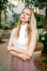 A blonde woman is standing in city park