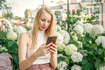 A woman is taking a selfie in front of white flowers