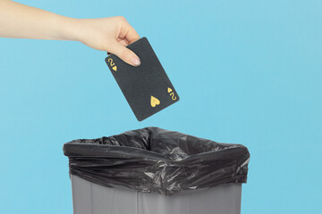 Throwing black playing card hearts 2 into the trash can, outstretched hand with playing card in front of trash can