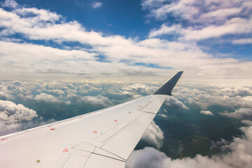 Obraz premium Flight view showing airplane wing above fluffy clouds blue sky during travel