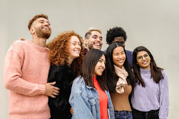Diverse group of young friends laughing together outdoors – Unity, happiness, community and friendship concept