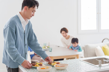 Obraz premium 家族で食べる料理を配膳する父親
