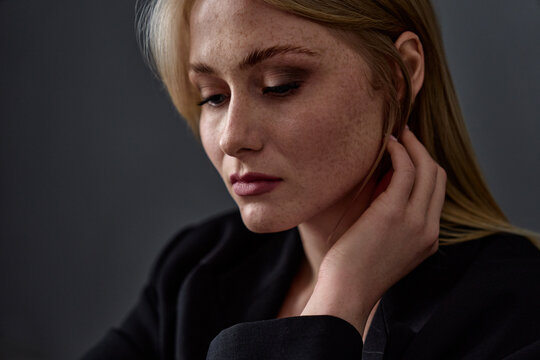 Close-up portrait of a thoughtful young woman in subdued lighting, showcasing her natural beauty and contemplative mood, emphasizing grace and a sense of reflection.