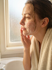 A woman is washing her face with a towel