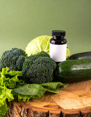 A bottle of pills is on top of a wooden table with a bunch of broccoli
