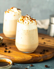 A glass of coffee with whipped cream on a wooden table