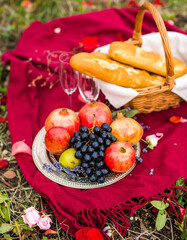 A plate of fruit including pears and grapes is on a red cloth