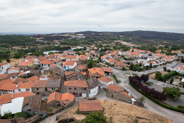 Fototapeta premium Vista aérea e panorâmica da histórica vila de Penedono no norte de Portugal, enquadrada por montanhas cobertas de vegetação com vestígios de uma grande área queimada ao fundo num dia nublado