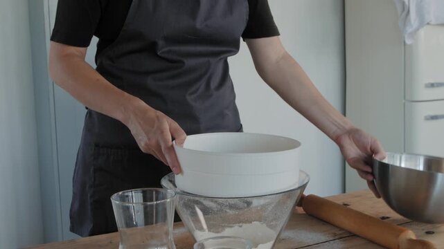 Woman chef sifting flour for dough preparation