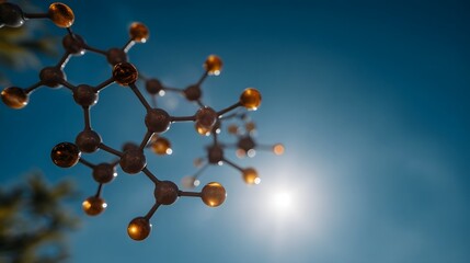 A glowing molecular structure composed of amber atoms and dark links is set against a vibrant blue sky with bright sunlight
