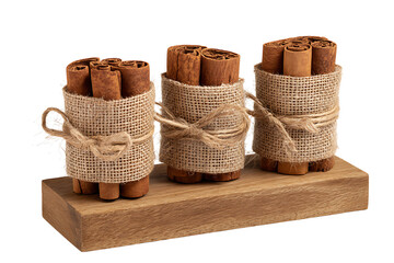Three bundles of cinnamon sticks tied with burlap on a wooden board isolated on transparent background