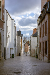 Perspective view of Rue de la Poterne in Orleans, France. Historic cobblestone street lined with medieval half-timbered houses and stone facades. Old town architecture in Loiret region.