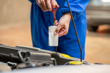 Close up of a car mechanic checking oil level in a mechanical at workshop