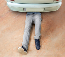 High angle shot of an unrecognizable man working under his car at home