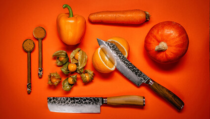 A pumkin, orange pepper belle, physalis fruits and a carrot with knives on an orange  background