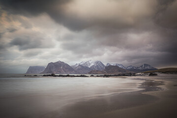 Snow capped mountains over calm Arctic beach Lofoten Islands Norway winter