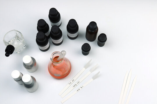 chemical beaker or flask is used on white table with blotting paper fragrance bottle and essential oil bottle are used to blend nice scent for making perfume and reed diffuser by perfumer in lab test