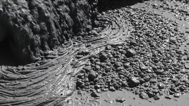 Thick Mud Flows and Spreads Across Rocky Ground in Harsh Sunlight