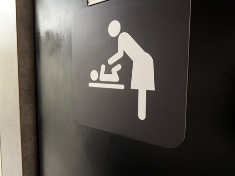 Sign on entrance door to nursery for diaper changes. Symbol of mother changing her baby diaper. Facilities in public place for parents with infants. Changing your baby diaper