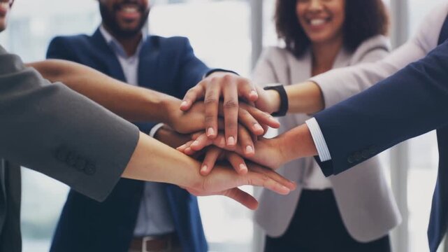 diverse group of people stacking their hands together in unity