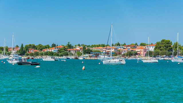 A small bay with moored boats in the Croatian town of Umag, viewed from the promenade on a sunny summer day.