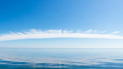 Calm blue ocean water horizon with clear sky and soft white cloudscape view