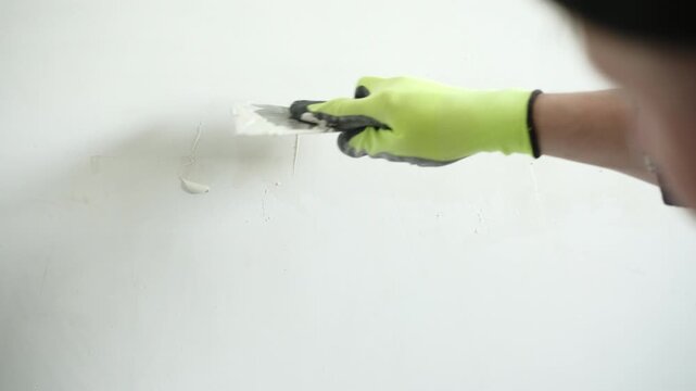 Handyman Plastering A Wall While Applying Wall Putty With A Spatula