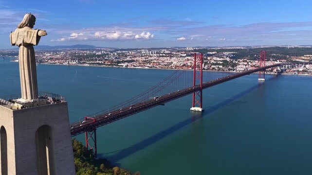 Aerial Drone Footage of Cristo Rei Monument Beside the 25 de Abril Suspension Bridge Over the Tagus River in Lisbon, Portugal &ndash; Iconic Architecture and Scenic Waterfront View