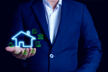 Businessman holding smart home icon with digital finance and property investment symbols, representing modern real estate technology.